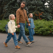Father walking holding hands with his two daughters