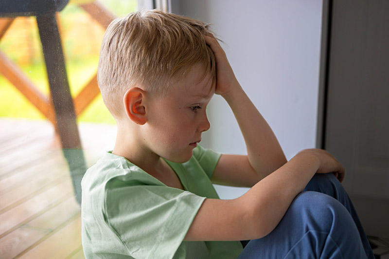 Young boy sat down looking upset