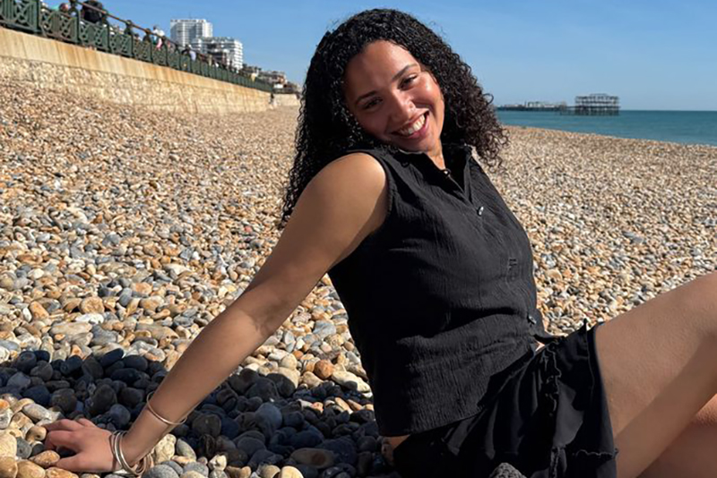 Photo of Aisha on a pebble beach