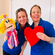 Two women from musical mayhem holding a puppet and heart
