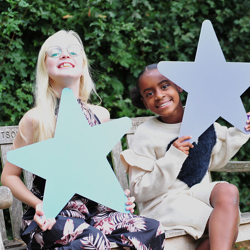Two girls holding SeeSaw stars