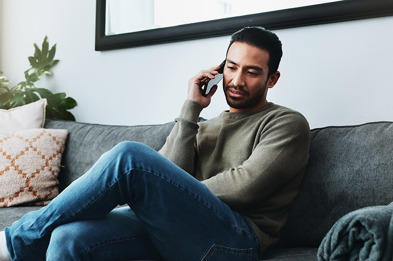 Man sat on the sofa talking on his mobile phone