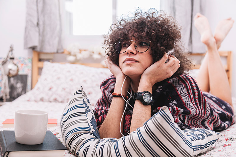 Teenager with headphones lying on their bed
