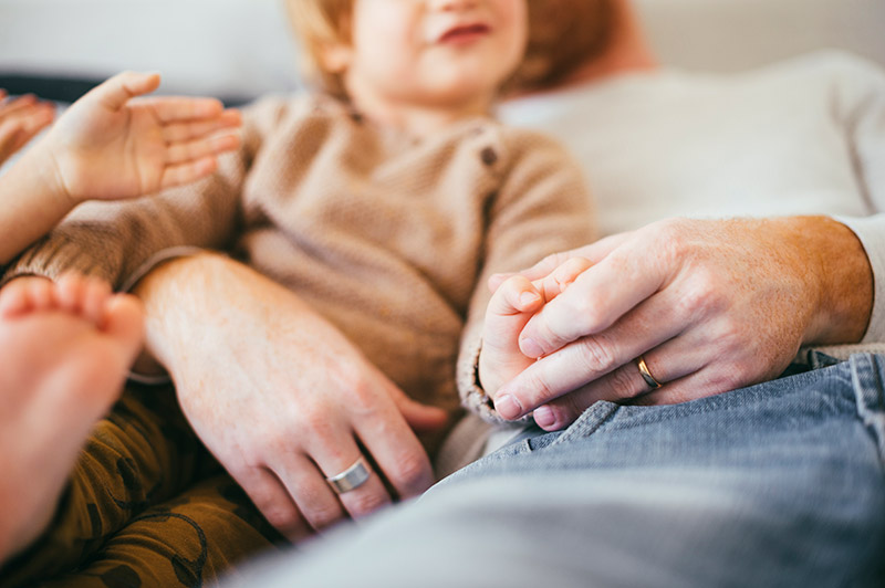 Dad sitting with a toddler holding his hand