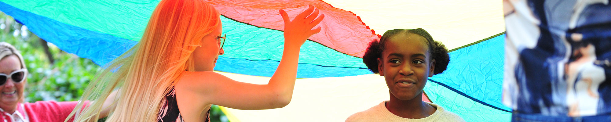 two girls playing under a parachute