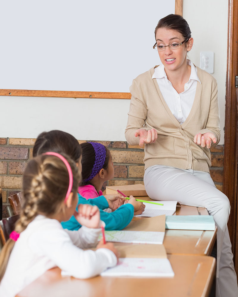 Teacher talking to young students in the classroom